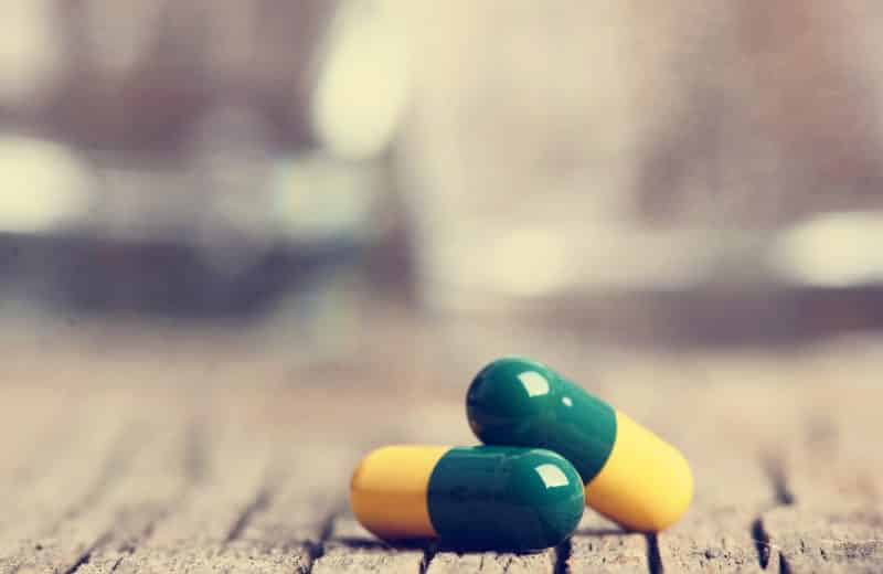 Two pills on wooden background