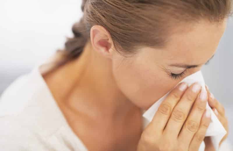 Woman blowing nose into handkerchief. allergies