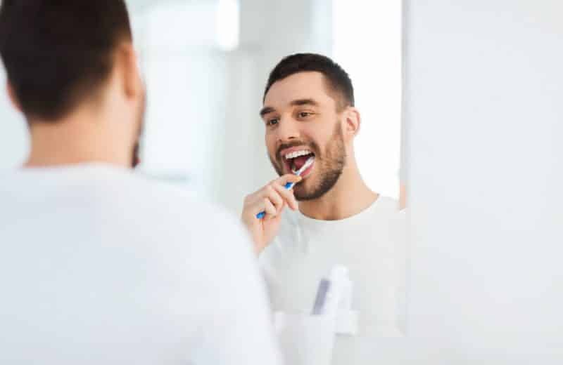 Man looking in mirror while brushing teeth