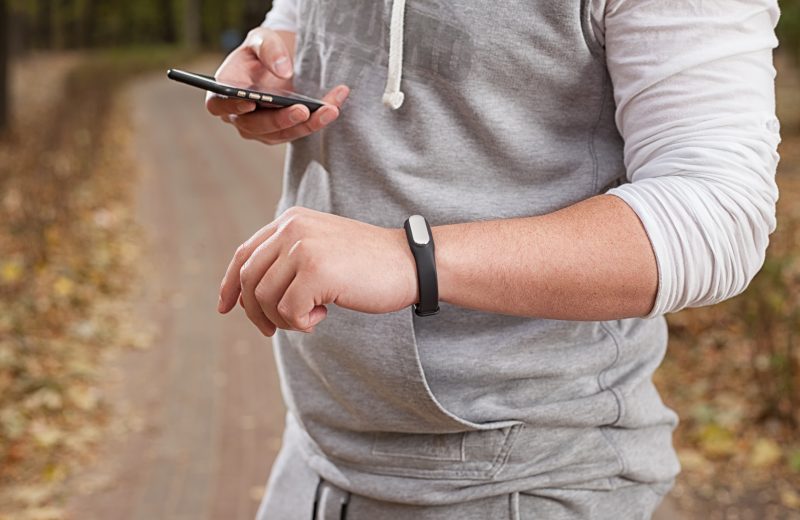 Young man using fitness bracelet during morning run