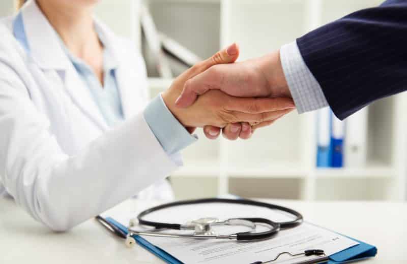Female doctor shaking hand with businessman in the office