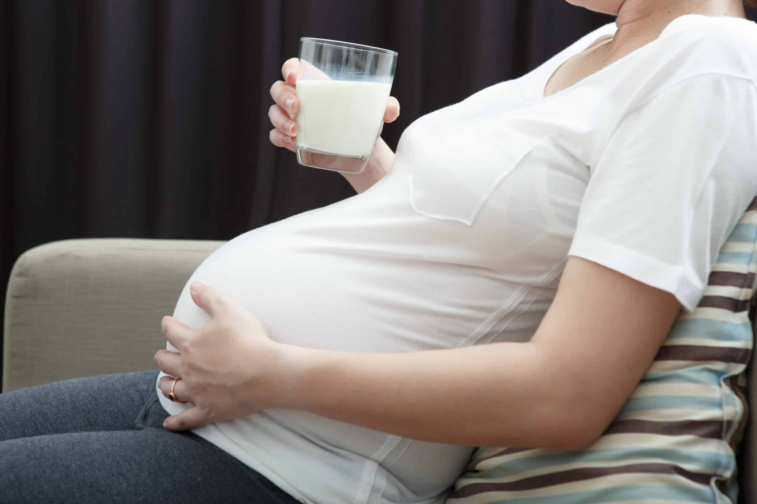 CloCould Carnitine could protect against Autism?se up neck-down shot of pregnant woman in white t-shirt sitting on couch holding a glass of milk