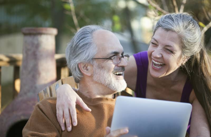Mature couple laughing while sharing a digital tablet. Technology that helps older adults.