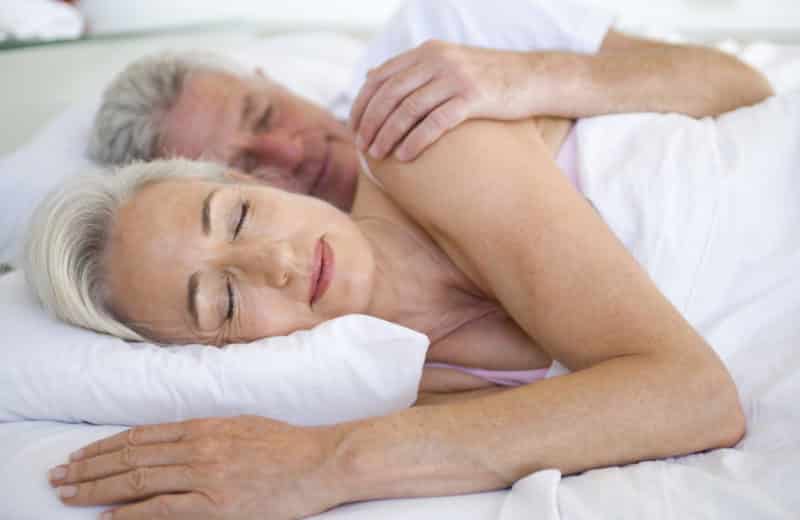 Older couple asleep in bed together