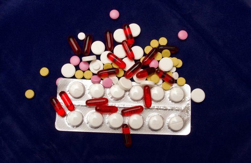 Medication adherence comes down to motivation. Image shows pile of caplets and tablets on top of medication container.