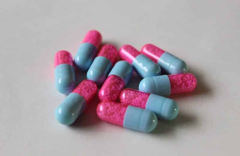 What you need to know about safely stopping antidepressants. Image is of pile of pink and blue capsules on grey table.