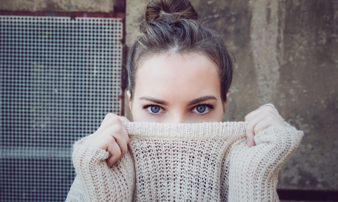 The 4 gynecological cancers women need to know about: image is of young woman looking straight at camera pulling sweater up over her mouth