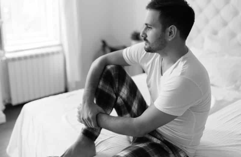 Man seated on bed preoccupied