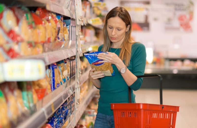 Woman doing shopping in grocery store reading food label