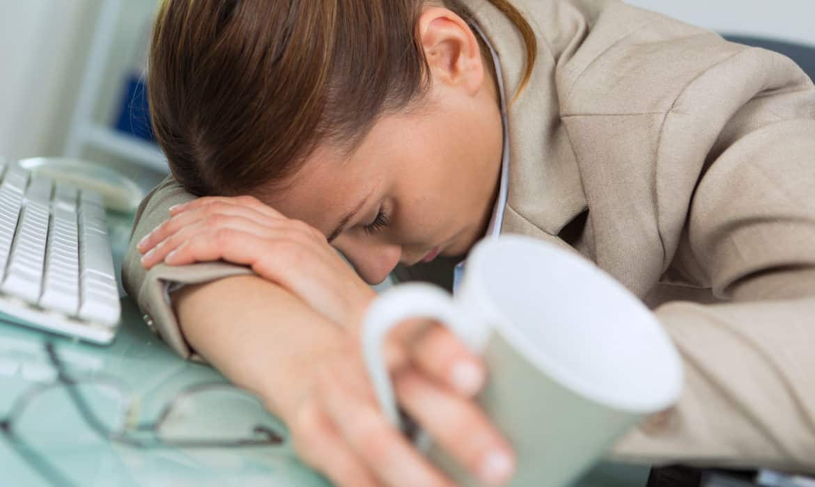 Woman asleep at her desk with coffee chronic fatigue