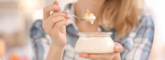 Young woman eating tasty yogurt, closeup