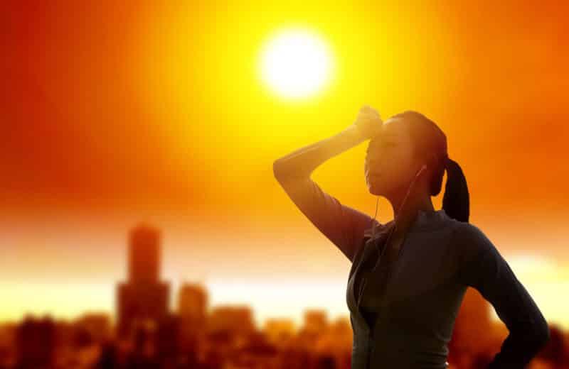 Woman overheating with city skyline in the background and bright sun