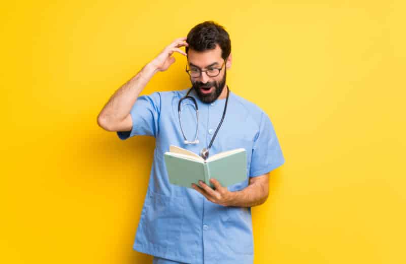Surgeon doctor man surprised while enjoying reading a book