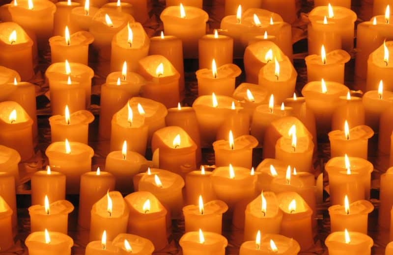 dozens of yellow candles burning in rows