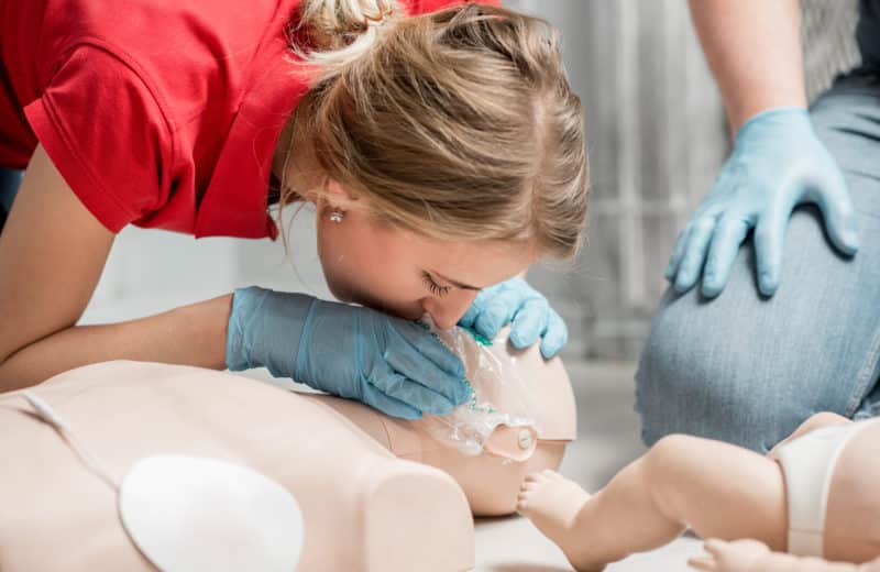 First aid training. Woman practicing CPR on a dummy