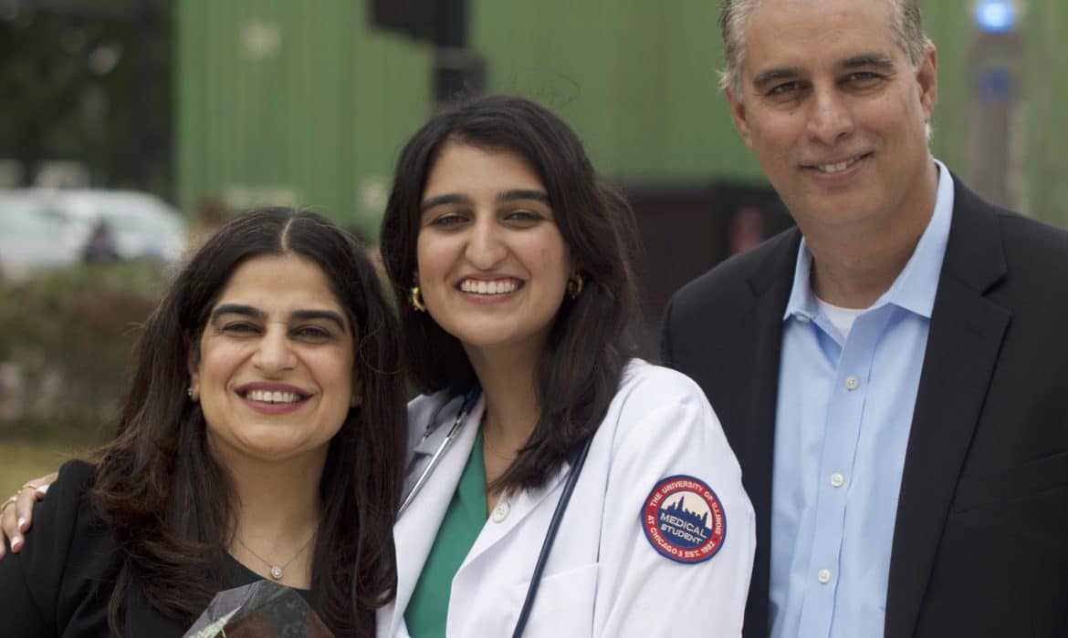 Medical student Hana Ahmed smiles, standing between her parents, at a White Coat Ceremony