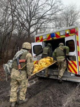 Men in military gear load a patient into an ambulance in Ukraine.