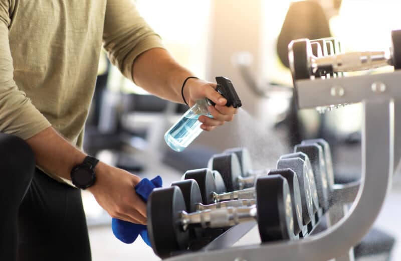 Wiping clean gym equipment to avoid germs, viruses, bacteria
