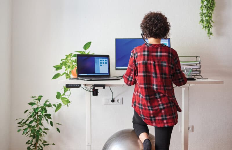Woman working at a standing desk to avoid being sedentary and getting some movement