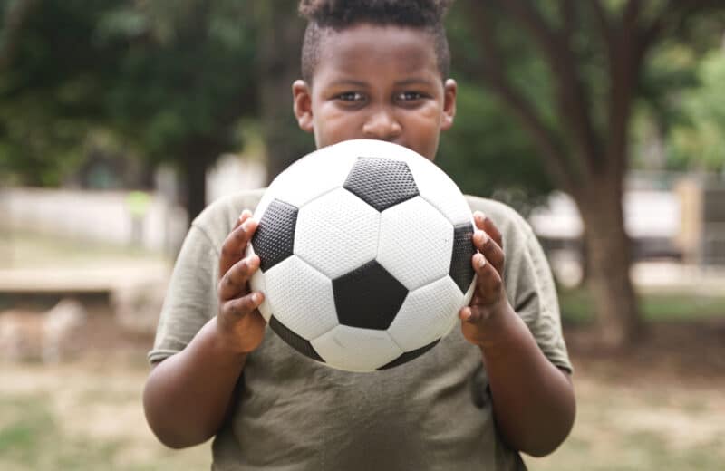 Overweight child holding soccer ball combating pediatric obesity