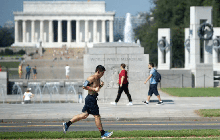 A man runs outdoors in Washington, D.C. as people walk in the background.