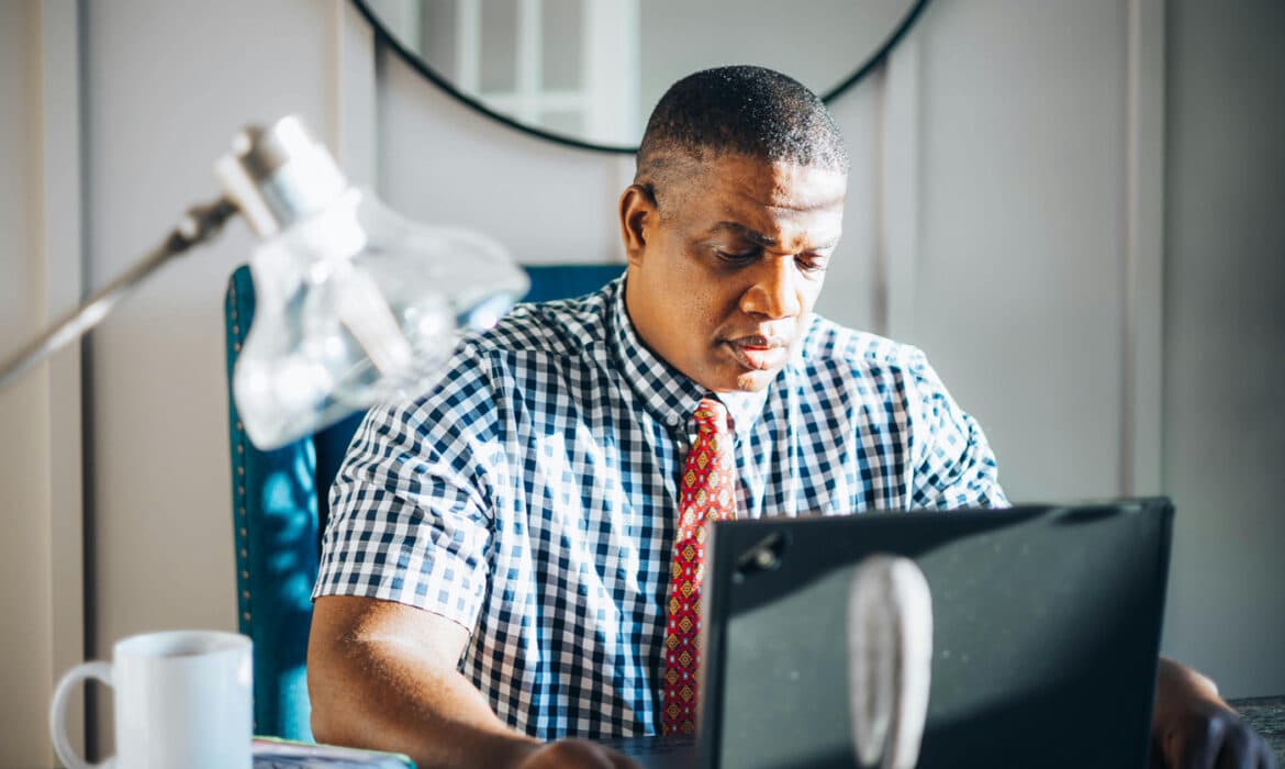 Man reading behind a laptop screen