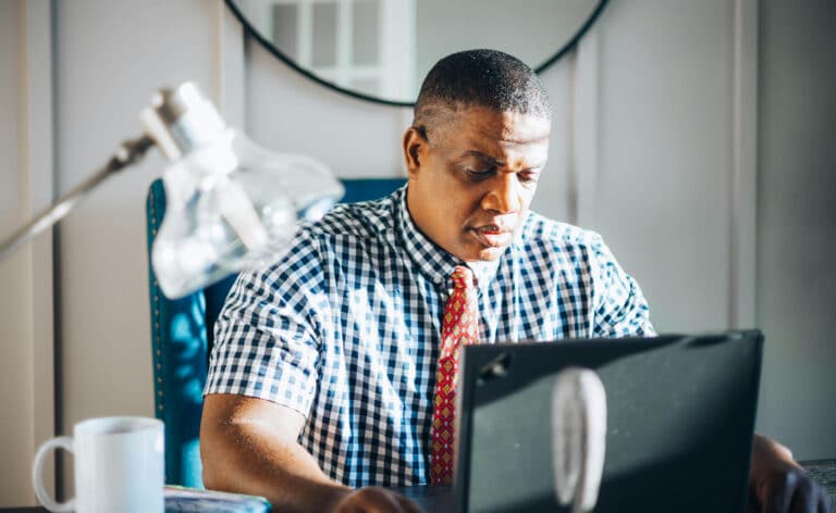 Man reading behind a laptop screen