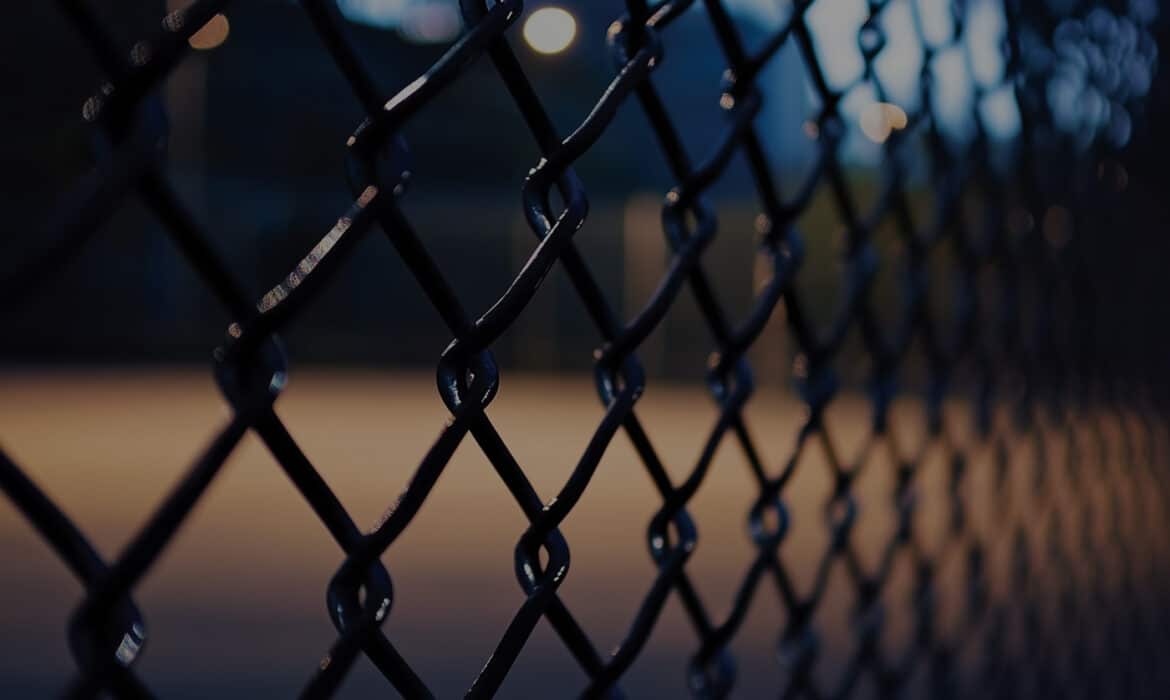 Dark playground seen through a foreboding chain link fence