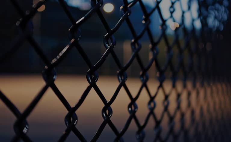 Dark playground seen through a foreboding chain link fence