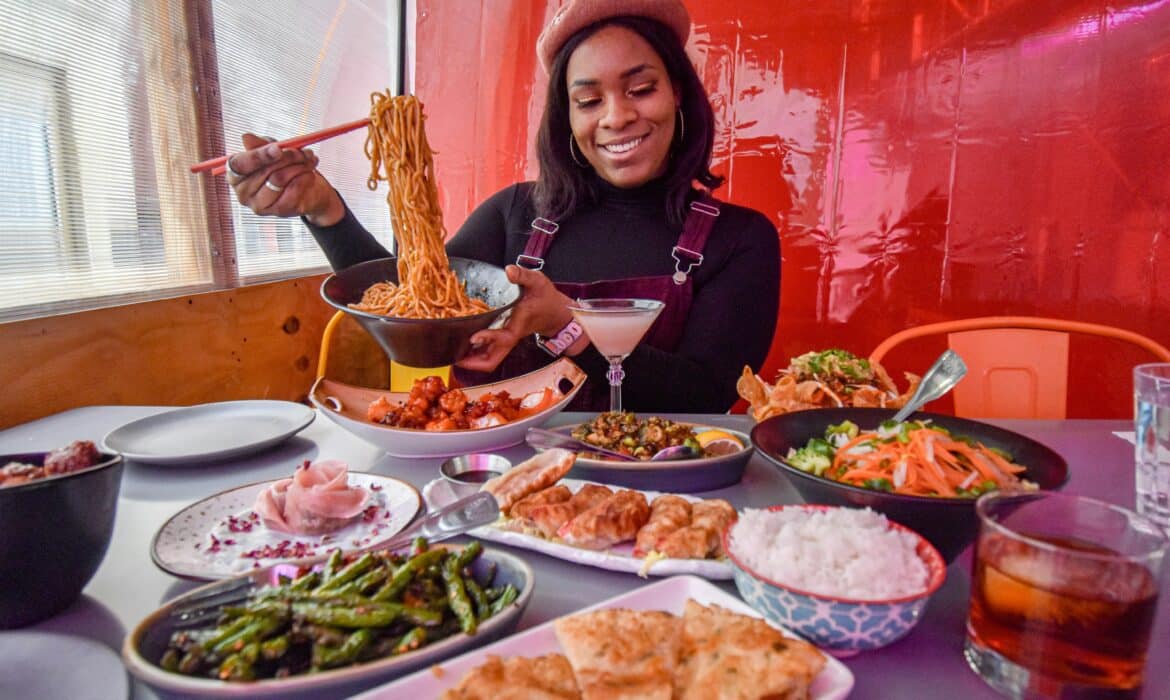 A woman sits smiling before a table of food.