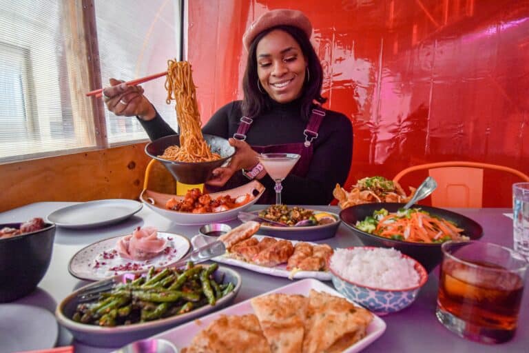 A woman sits smiling before a table of food.