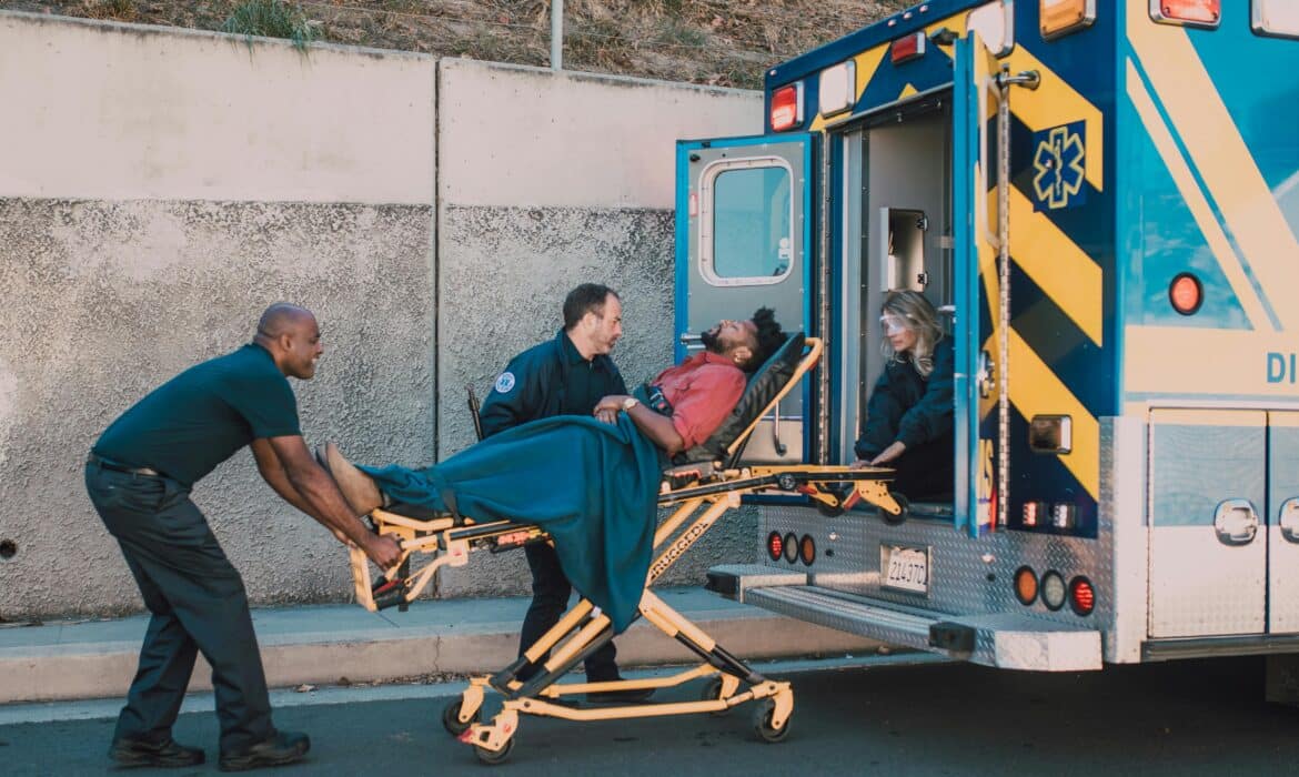 Paramedics load a patient into an ambulance parked on the side of the road.