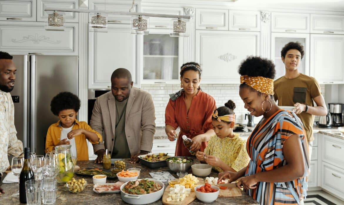 A family gathers around a counter, preparing a meal full of healthy fruits and vegetables.