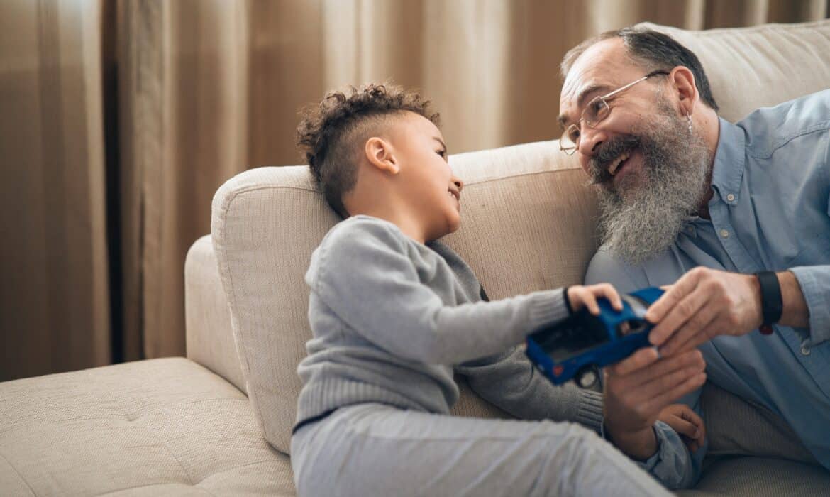 A psychologist sits on a couch with a young boy, playing with a toy truck