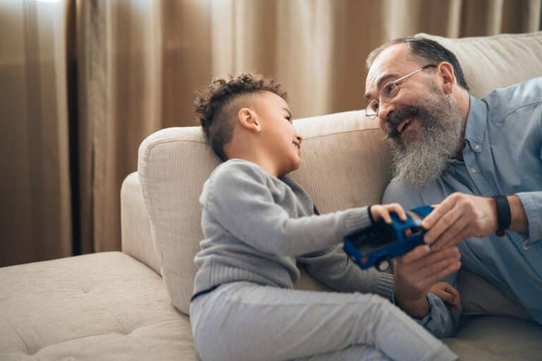 A psychologist sits on a couch with a young boy, playing with a toy truck