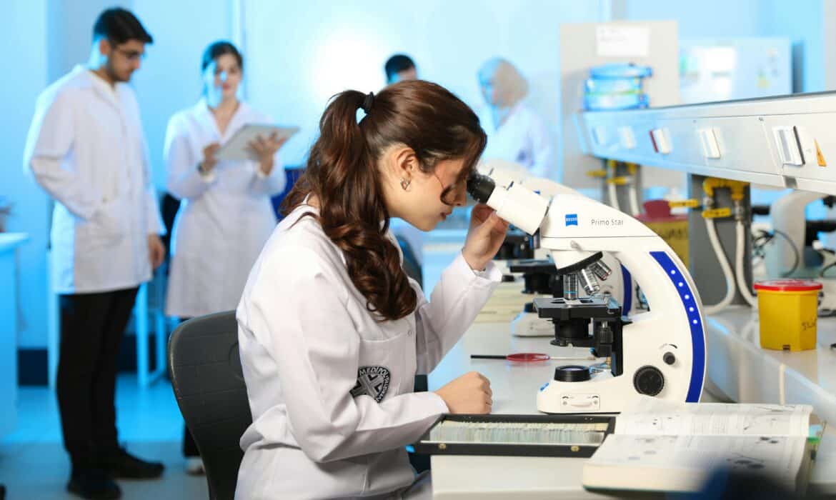Researchers in a laboratory study samples through a microscope.