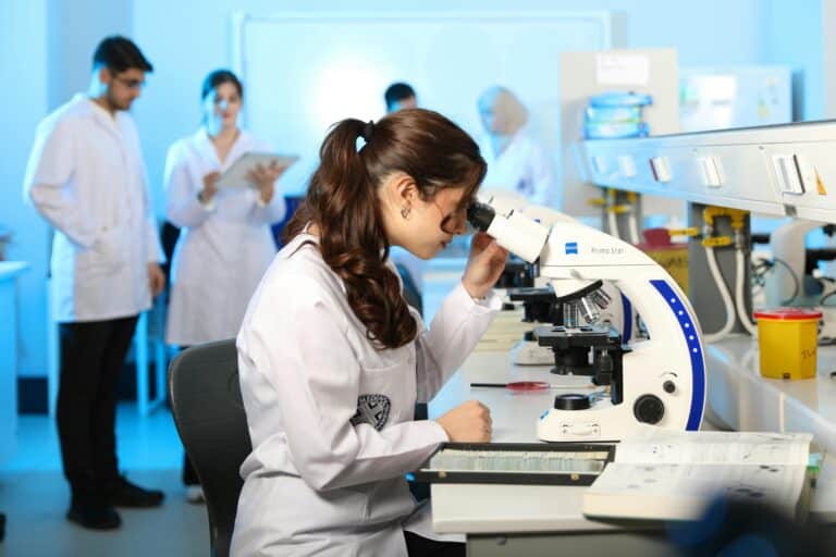 Researchers in a laboratory study samples through a microscope.