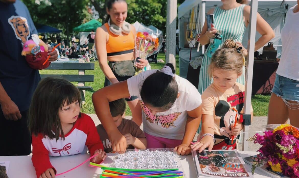 Children at a Chicago farmers market gather around a table for Kid's Lit Day, to make alphabet-bead bracelets.