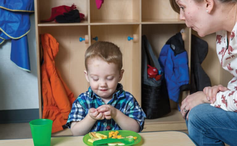 Adult attempting to get child to eat their food