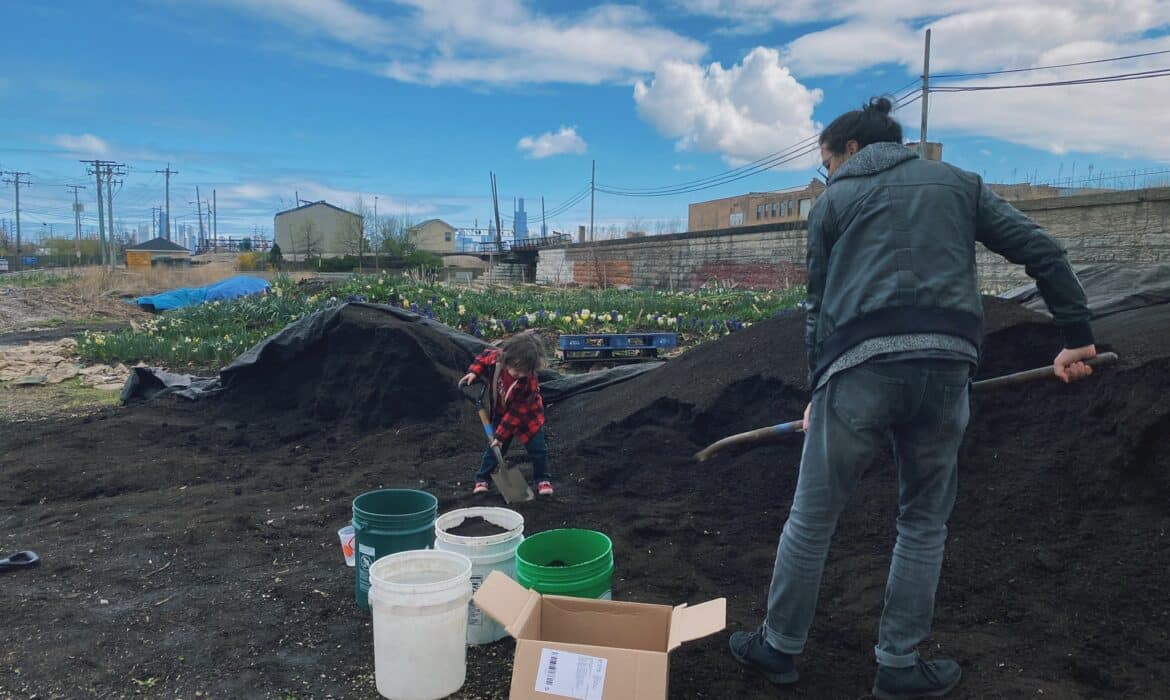A man and child shovel finished compost into buckets at a site on Chicago's west side.