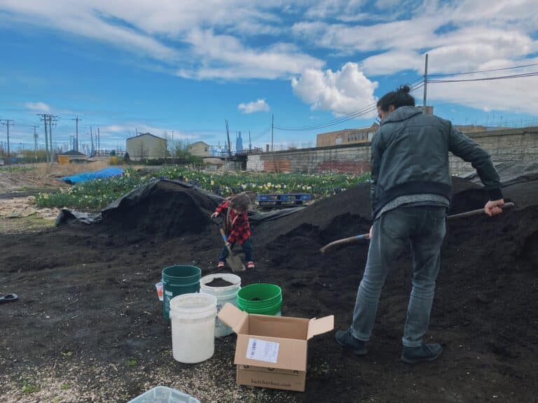A man and child shovel finished compost into buckets at a site on Chicago's west side.