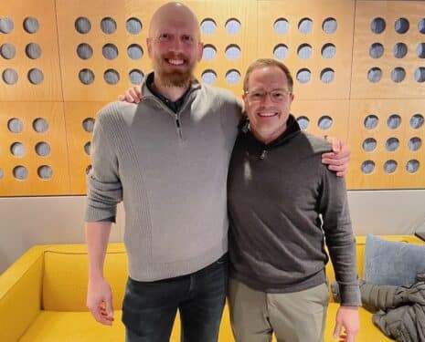 Dan Dean and Ian Hughes stand before wooden wall art at Chicago Recording Company.