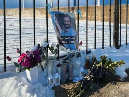 A memorial for Alex Pretti outside of the Jesse Brown VA Hospital in Chicago includes flowers, candles, and a photo of Pretti in scrubs.