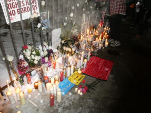 Glowing candles line a fence outside the Jesse Brown VA in Chicago, in honor of Alex Pretti