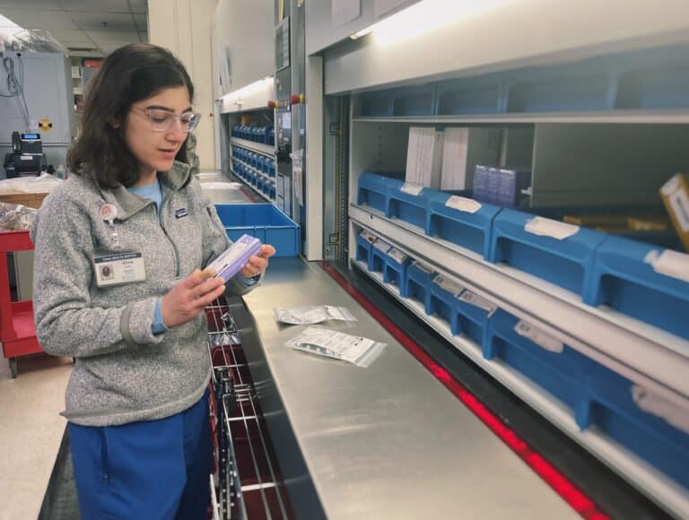 A Sinai Chicago pharmacist looks at the label on a bottle of medication before filing it.