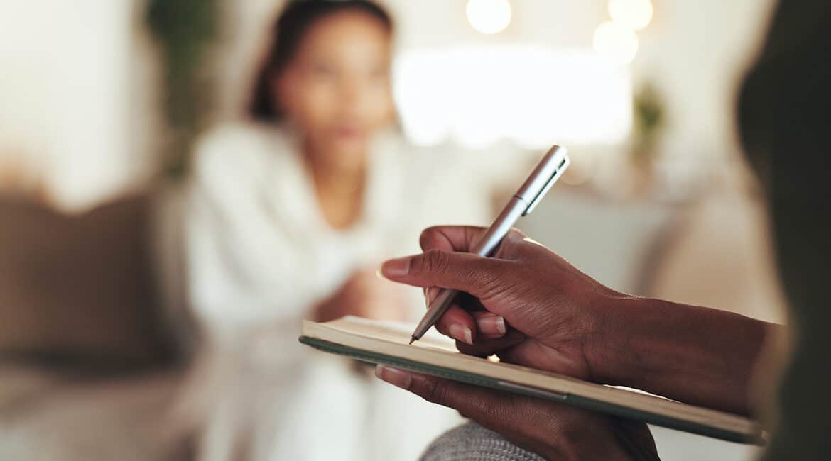 Meridian Psychiatric image of a patient with a psychiatrist, a mental health specialist, writing notes during a session