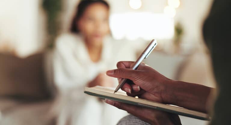 Meridian Psychiatric image of a patient with a psychiatrist, a mental health specialist, writing notes during a session
