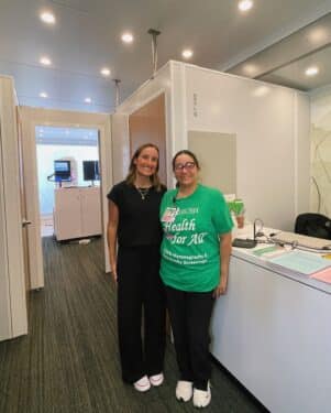 A nurse and receptionist welcome patients into the mobile mammogram clinic.