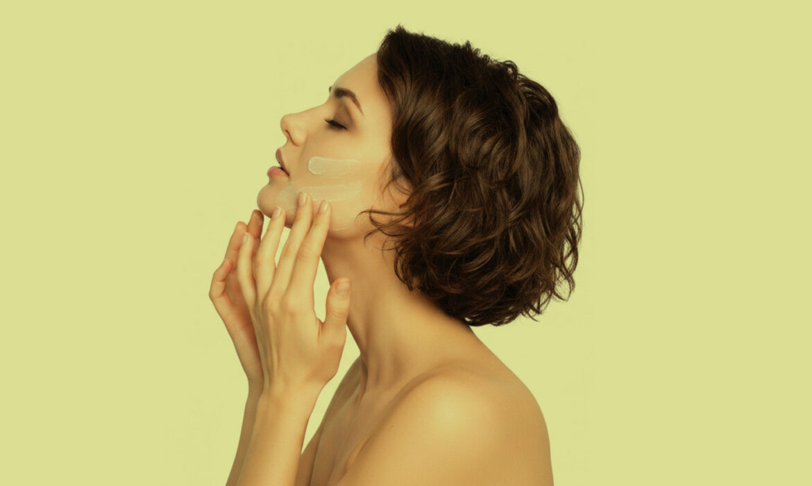 A woman applies sunscreen to her face. Skin care represented.