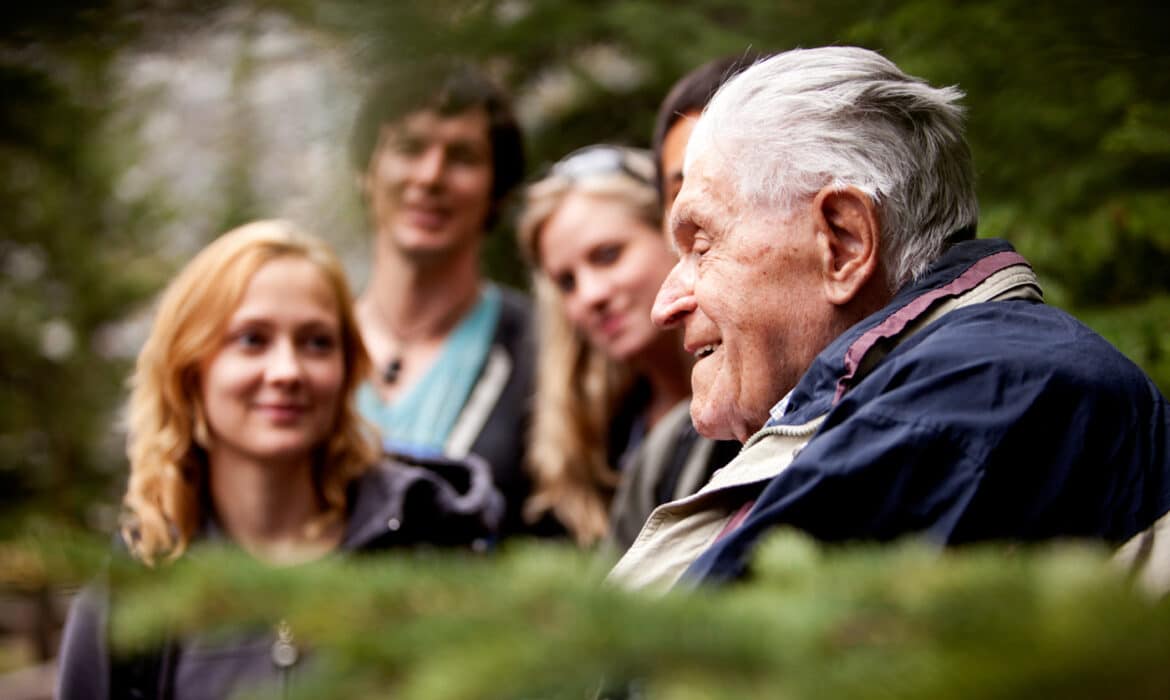 Multigenerational people gather around an elderly relative listening attentively